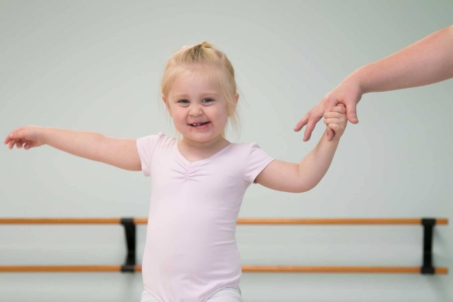 toddler in a pink leotard taking part in a mommy & me dance class